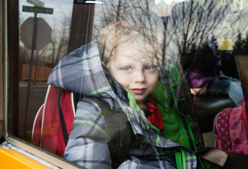 Portrait of smiling boy seen through school bus window